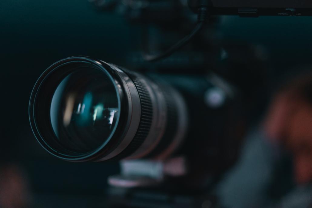 Mit einem Teleobjektiv auf einer Videoproduktion in Berlin arbeiten. Im Close-Up blicken wir schräg von vorne auf die Linse eines Teleobjektivs während einer Videoproduktion in Berlin.